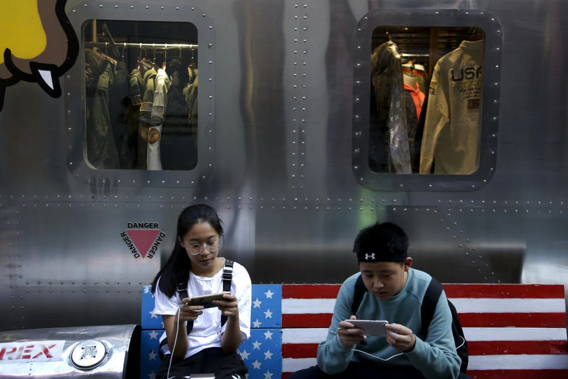 Shoppers browse their phones outside a fashion boutique selling US brand clothing in a Beijing shopping mall. China and the US have clashed about how the WTO should reform to better serve member interests. (AP Photo)