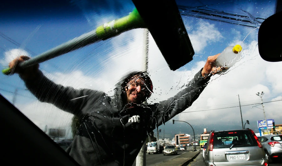 A Venezuelan migrant cleans a windshield at a street corner in Quito, Ecuador. (AP)