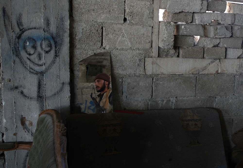 A Syrian rebel-fighter from the National Liberation Front (NLF) is reflected in a mirror as he takes position on the frontline facing government forces in the al-Rashedin area west of Aleppo in northwestern Syria, on November 20, 2018. (AFP)
