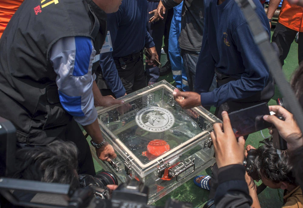 In this Nov. 1, 2018, file photo, members of the National Transportation Safety Committee lift a box containing the flight data recorder from a crashed Lion Air jet onboard a rescue ship anchored in the waters of Tanjung Karawang, Indonesia. (AP Photo/Fauzy Chaniago, File)
