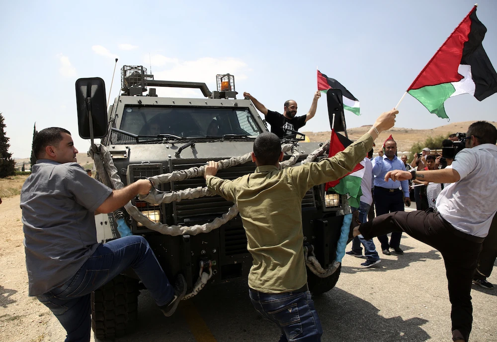 Protesters target an Israeli military vehicle in Bardala earlier this year. Church authorities have demanded the return of land seized by Israel. (AFP)