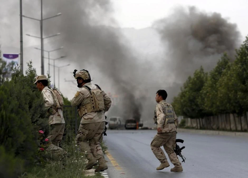 A Taliban attack on a foreign compound in Kabul has left at least 12 people injured. Above, members of the Afghan security forces cross a road after an attack near the parliament in Kabul. (Reuters)