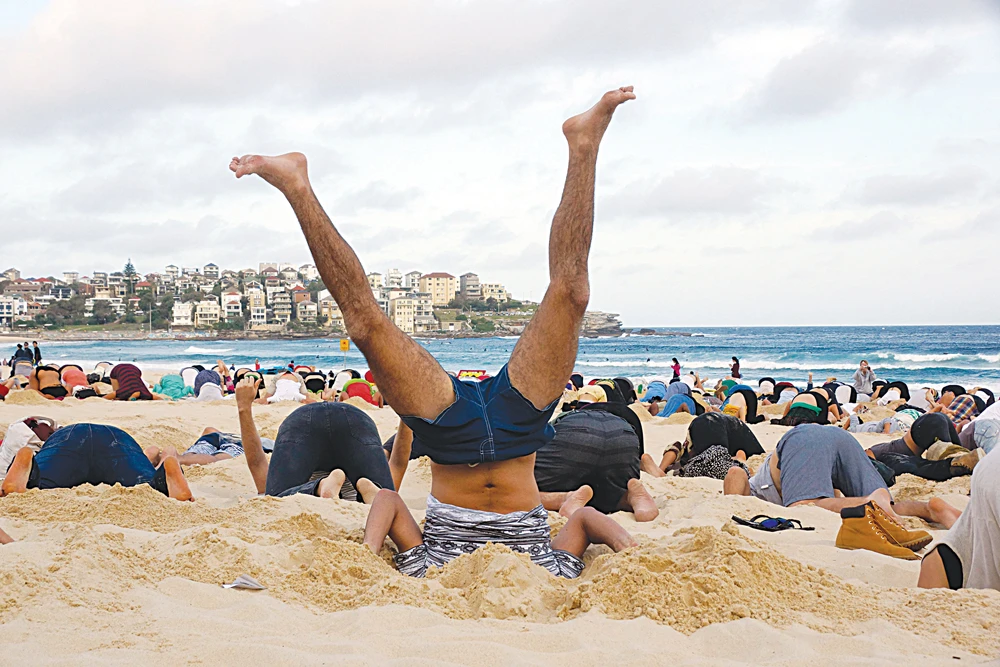 Protesters bury their heads in the sand over inaction on climate change at the 2014 summit in Australia. (Reuters)