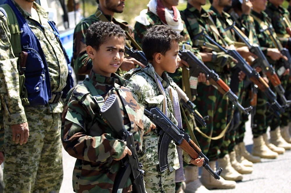 Yemeni children accompanied by their fathers hold weapons during a gathering in Sanaa to show support for the Houthis on September 27, 2018. (File/AFP)