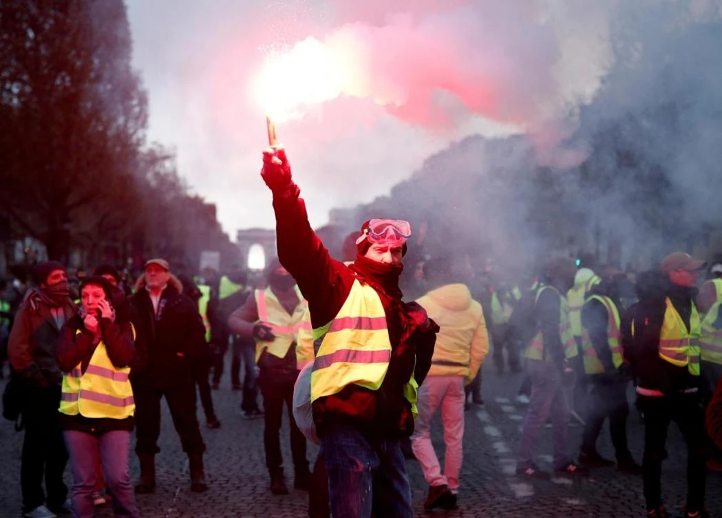A protester wearing a yellow vest symbolizing French drivers' protest against higher fuel prices burns flare. (Reuters)