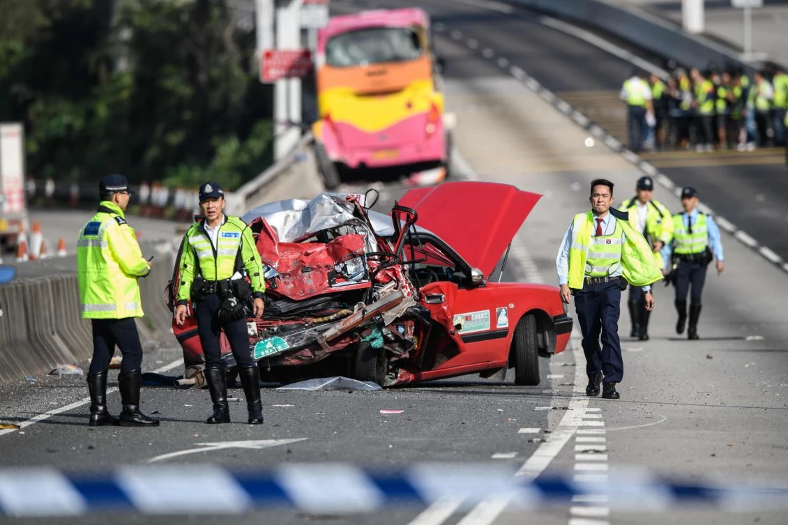 Police walk past a crushed taxi after a coach (back) collided with it in Hong Kong on November 30, 2018. (AFP)