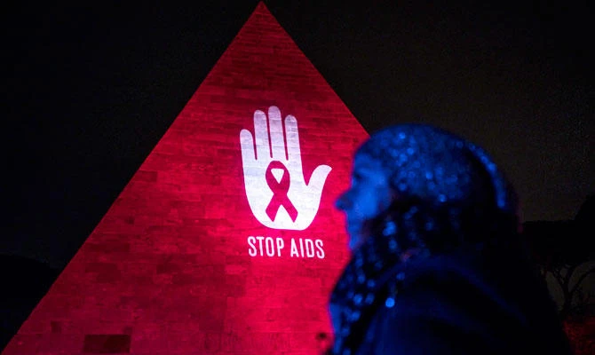 A woman walks by the Pyramid of Cestius is illuminated in red for the World AIDS Day, in Rome, on Friday, Nov. 30 2018. (AP)