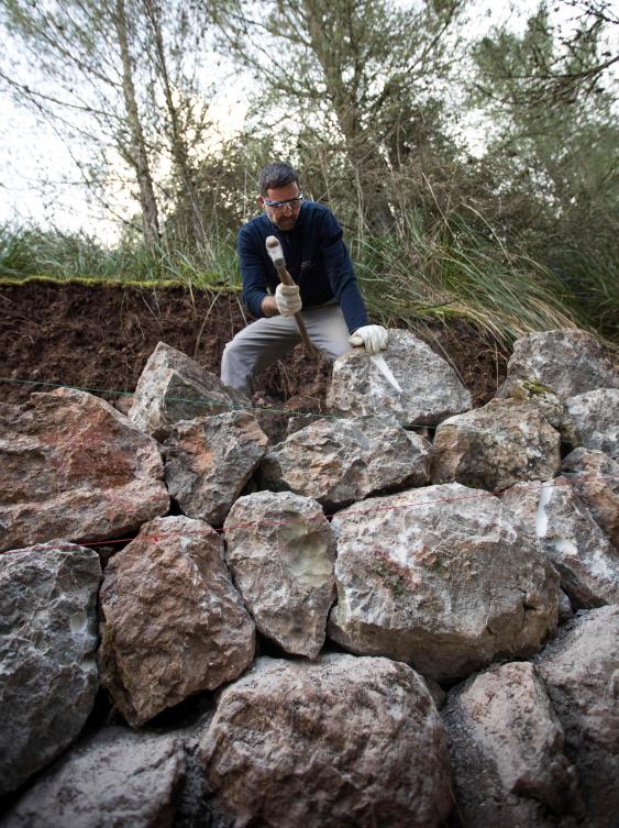 A man uses the dry stone technique to biuld a wall in Esporles on the Spanish Balearic Island of Mallorca on December 11, 2018. The art of dry stone walling, inscribed in 2018 on the Representative List of the Intangible Cultural Heritage of Humanity, (sometimes called drystack) is a building method by which structures are constructed from stones without any mortar to bind them together. Dry stone structures are stable because of their unique construction method, which is characterized by the presence of a load-bearing facade of carefully selected interlocking stones. / AFP / JAIME REINA