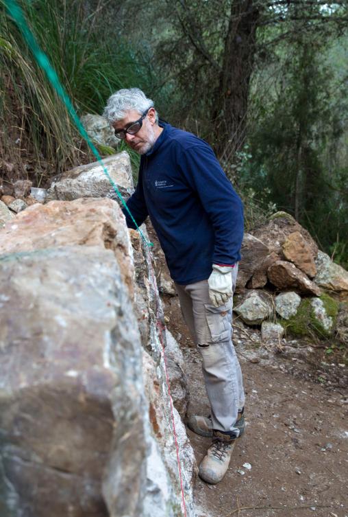A man uses the dry stone technique to biuld a wall in Esporles on the Spanish Balearic Island of Mallorca on December 11, 2018. The art of dry stone walling, inscribed in 2018 on the Representative List of the Intangible Cultural Heritage of Humanity, (sometimes called drystack) is a building method by which structures are constructed from stones without any mortar to bind them together. Dry stone structures are stable because of their unique construction method, which is characterized by the presence of a load-bearing facade of carefully selected interlocking stones. / AFP / JAIME REINA