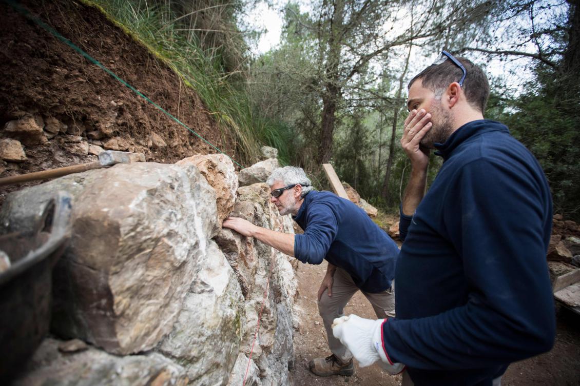 Two men build a wall using the dry stone technique in Esporles on the Spanish Balearic Island of Mallorca on December 11, 2018. The art of dry stone walling, inscribed in 2018 on the Representative List of the Intangible Cultural Heritage of Humanity, (sometimes called drystack) is a building method by which structures are constructed from stones without any mortar to bind them together. Dry stone structures are stable because of their unique construction method, which is characterized by the presence of a load-bearing facade of carefully selected interlocking stones. / AFP / JAIME REINA