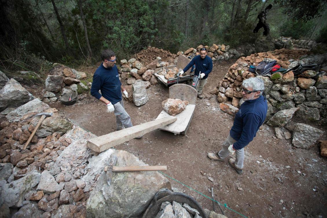 Some men build a wall using the dry stone technique in Esporles on the Spanish Balearic Island of Mallorca on December 11, 2018. The art of dry stone walling, inscribed in 2018 on the Representative List of the Intangible Cultural Heritage of Humanity, (sometimes called drystack) is a building method by which structures are constructed from stones without any mortar to bind them together. Dry stone structures are stable because of their unique construction method, which is characterized by the presence of a load-bearing facade of carefully selected interlocking stones. / AFP / JAIME REINA