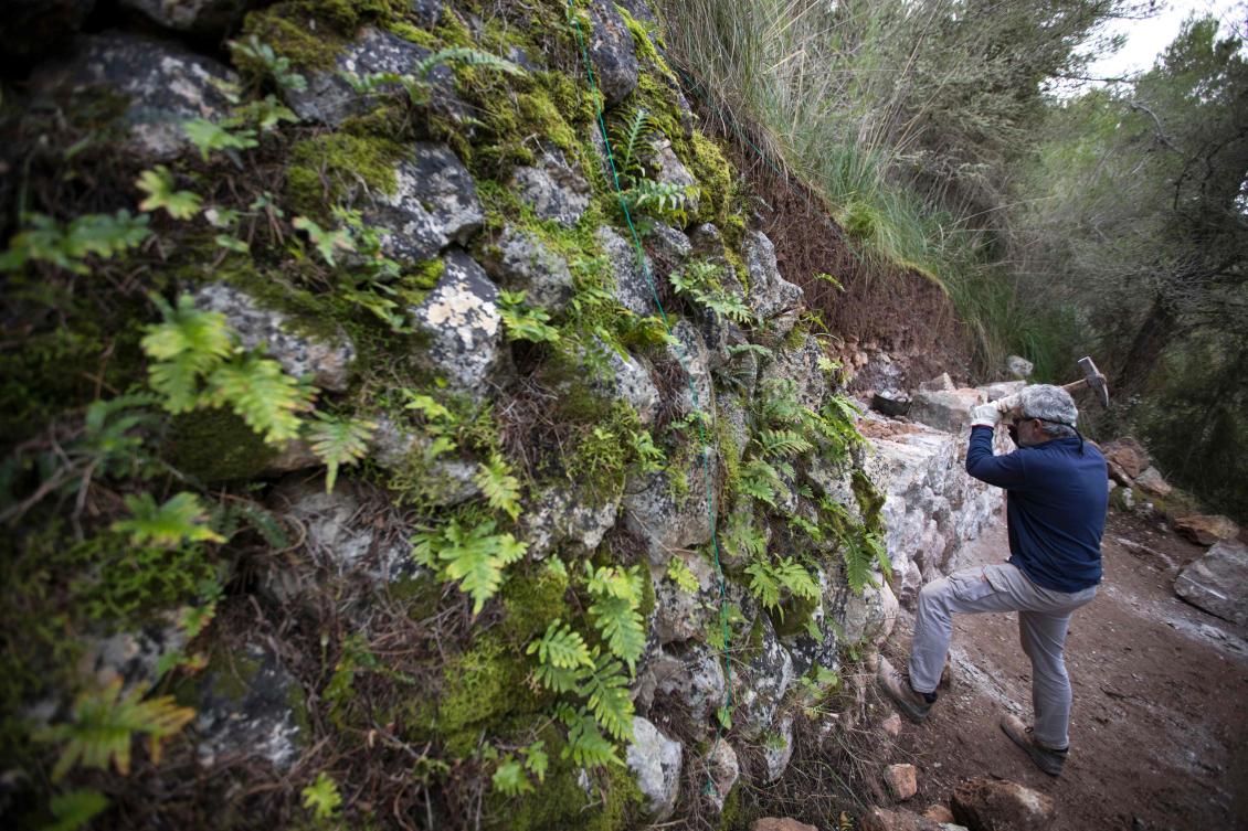 A man uses the dry stone technique to biuld a wall in Esporles on the Spanish Balearic Island of Mallorca on December 11, 2018. The art of dry stone walling, inscribed in 2018 on the Representative List of the Intangible Cultural Heritage of Humanity, (sometimes called drystack) is a building method by which structures are constructed from stones without any mortar to bind them together. Dry stone structures are stable because of their unique construction method, which is characterized by the presence of a load-bearing facade of carefully selected interlocking stones. / AFP / JAIME REINA