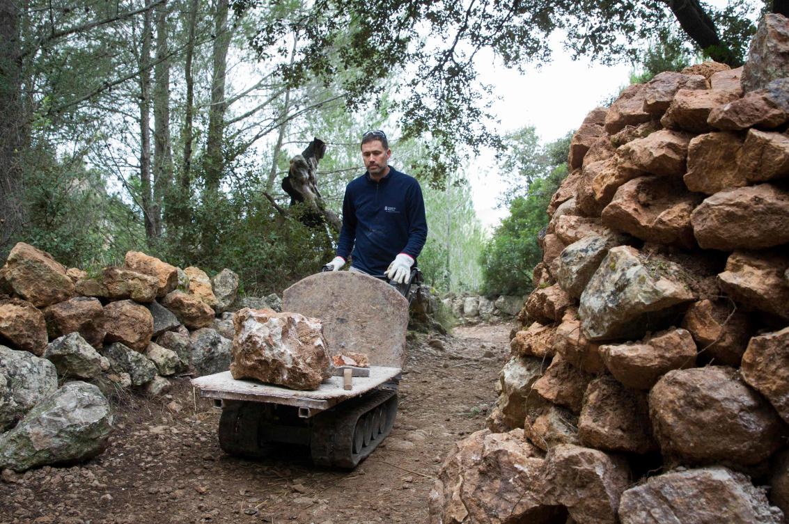 A man uses the dry stone technique to build a wall in Esporles on the Spanish Balearic Island of Mallorca on December 11, 2018. The art of dry stone walling, inscribed in 2018 on the Representative List of the Intangible Cultural Heritage of Humanity, (sometimes called drystack) is a building method by which structures are constructed from stones without any mortar to bind them together. Dry stone structures are stable because of their unique construction method, which is characterized by the presence of a load-bearing facade of carefully selected interlocking stones. / AFP / JAIME REINA