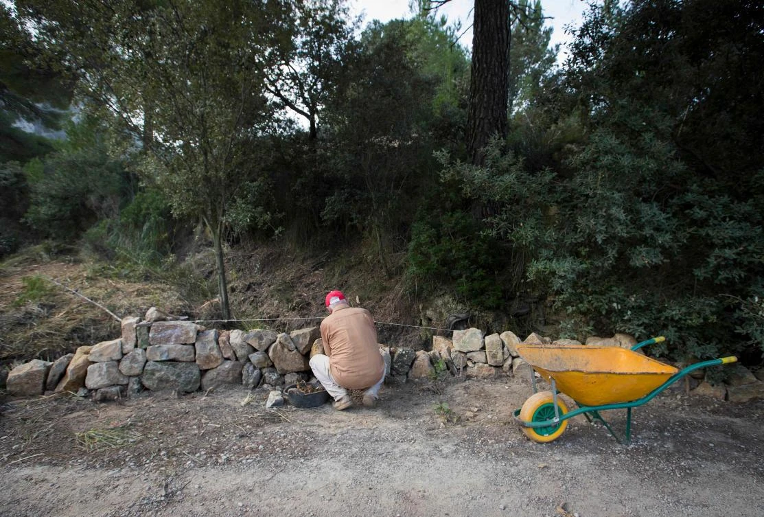 Tomeu Piza builds a wall in his farm using the dry stone technique in Esporles on the Spanish Balearic Island of Mallorca on December 11, 2018. The art of dry stone walling, inscribed in 2018 on the Representative List of the Intangible Cultural Heritage of Humanity, (sometimes called drystack) is a building method by which structures are constructed from stones without any mortar to bind them together. Dry stone structures are stable because of their unique construction method, which is characterized by the presence of a load-bearing facade of carefully selected interlocking stones. / AFP / JAIME REINA