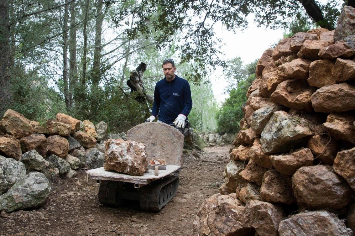 A man uses the dry stone technique to build a wall in Esporles on the Spanish Balearic Island of Mallorca on December 11, 2018. The art of dry stone walling, inscribed in 2018 on the Representative List of the Intangible Cultural Heritage of Humanity, (sometimes called drystack) is a building method by which structures are constructed from stones without any mortar to bind them together. Dry stone structures are stable because of their unique construction method, which is characterized by the presence of a load-bearing facade of carefully selected interlocking stones. / AFP / JAIME REINA
