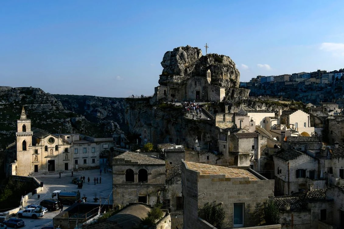 (FILES) This file photo taken on October 19, 2018 shows visitors walking towards the cave church Madonna de Idris (Rear C) in the southern Italian city of Matera, which has been selected as the 2019 European capital of culture. - / AFP / Filippo MONTEFORTE