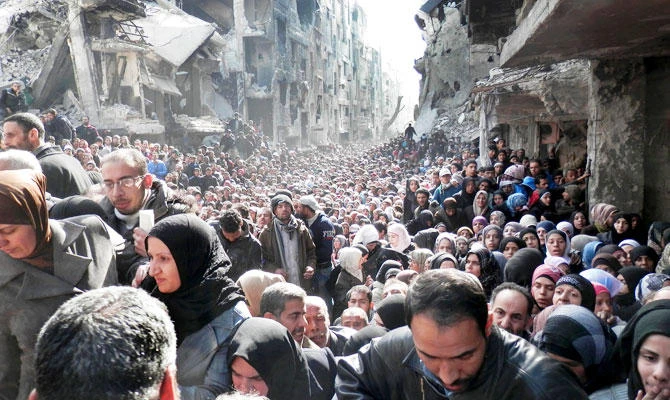 In this Jan. 31, 2014, file photo, released by the United Nations Relief and Works Agency for Palestine Refugees in the Near East (UNRWA), shows residents of the besieged Palestinian camp of Yarmouk, queuing to receive food supplies, in Damascus, Syria. (AP)