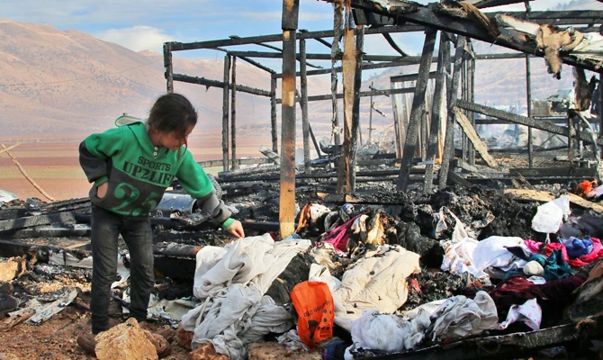 A young refugee looks clothes following a fire that ripped through a refugee camp in Lebanon. (AFP)