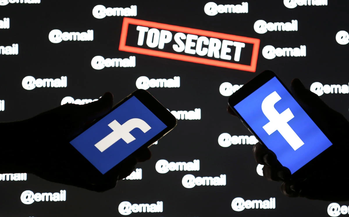 People hold smartphones with the Facebook logo in front of displayed "top secret" and "email" words. (Reuters)