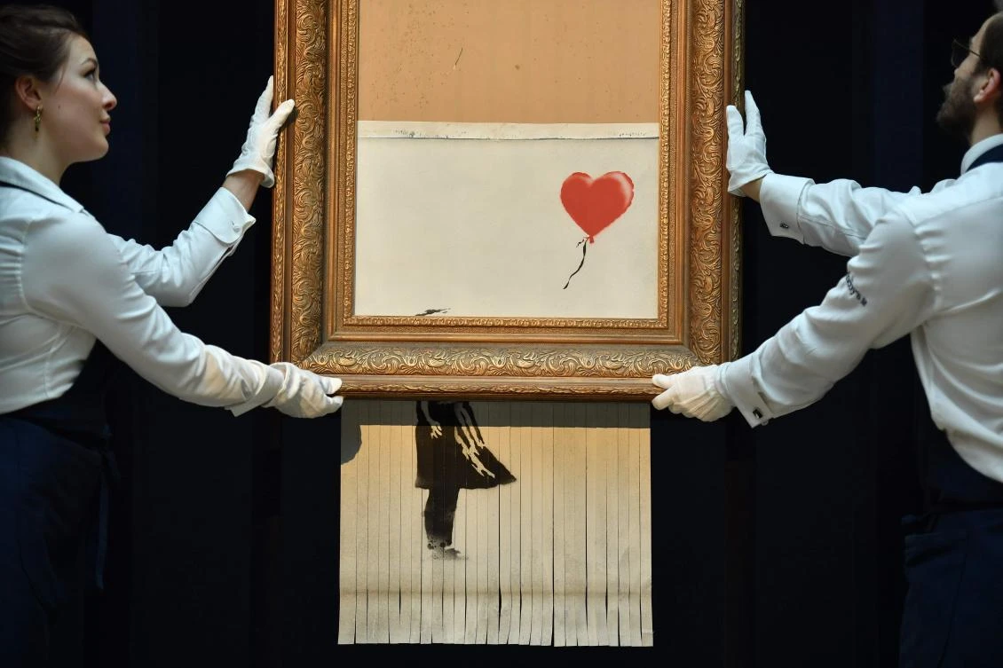 The buyer of a work by street artist Banksy that was partially destroyed moments after it sold has gone through with the purchase at Sotheby's auction house. (AFP)