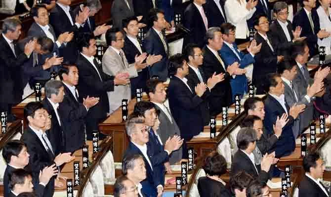 Members of Japan's lower house of parliament clap their hands as they stand up to support a bill during the plenary session in Tokyo on June 2, 2017. (AFP)