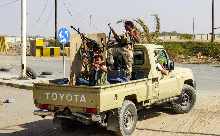 Yemeni pro-government forces cheer as they ride in the back of a pickup truck mounted with a machine gun. (File/AFP)