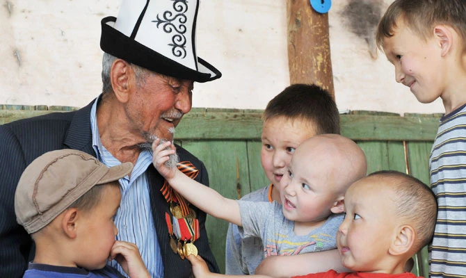 A photo taken on May 7, 2015 shows World War Two veteran Sardar Akylbekov, 93, playing with his grandchildren in front of his house in the village of Tok-Bay, some 20km of Kyrgyzstan's capital Bishkek. (AFP)