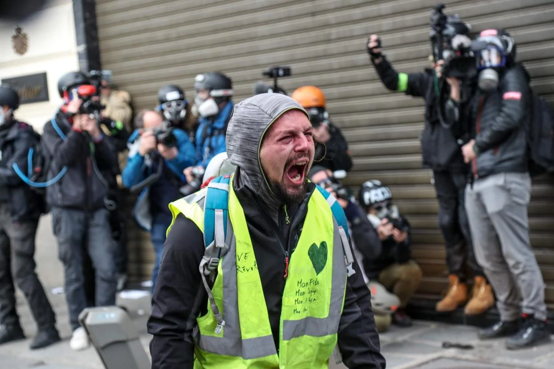 A ‘yellow vest” (gilet jaune) demonstrator faces riot police near the Champs Elysees in Paris during a mobilization against rising costs of living they blame on high taxes. (AFP)