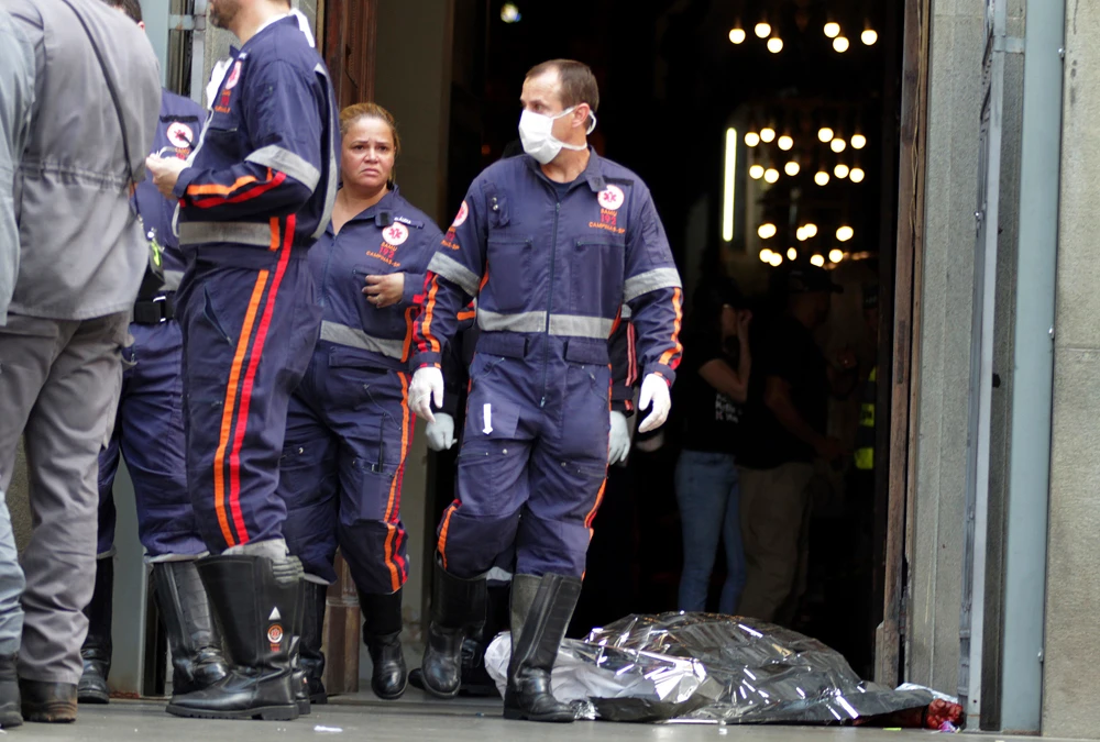 A firefighter walks next to a victim killed at the Metropolitan Cathedral in Campinas, Brazil. An armed man entered the cathedral and opened fire, killing at least four people before killing himself. (AP Photo)