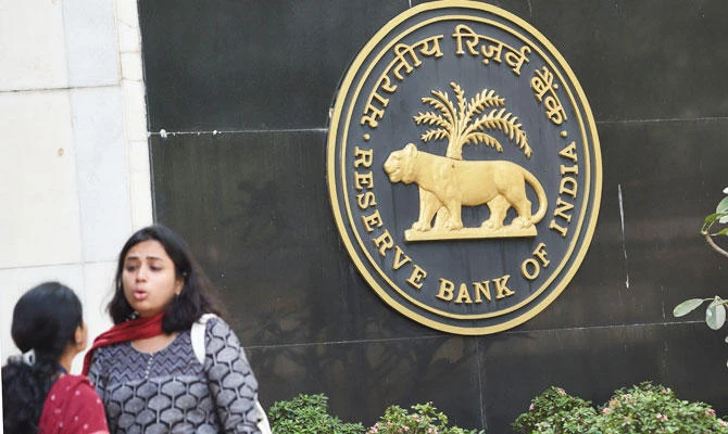 Visitors are seen standing next to a logo of the Reserve Bank of India (RBI) at the bank's head office in Mumbai on December 5, 2018. (AFP)