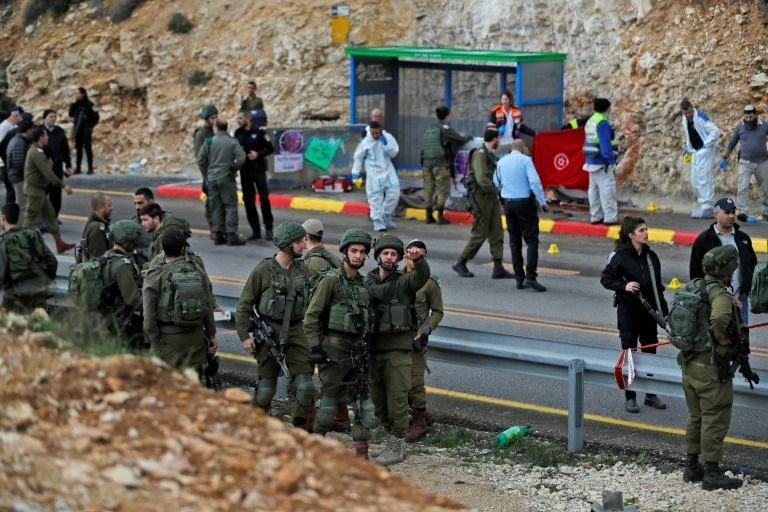 Israeli forces and forensic experts inspect the site of a Palestinian drive-by shooting in the West Bank. (AFP)