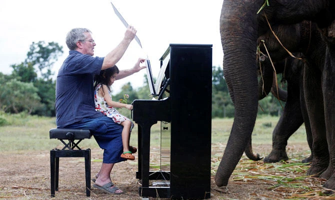 British volunteer Paul Barton and his daughter Emily Barton, 4, play piano for sick, abused, retired and rescued elephants in sanctuary along Thailand-Myanmar border in Kanchanaburi, Thailand, December 9, 2018. (REUTERS)