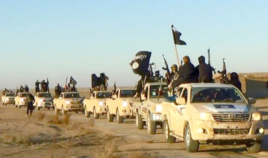 Daesh militants wave flags on their vehicles in a convoy on a road leading to Iraq. (AP)