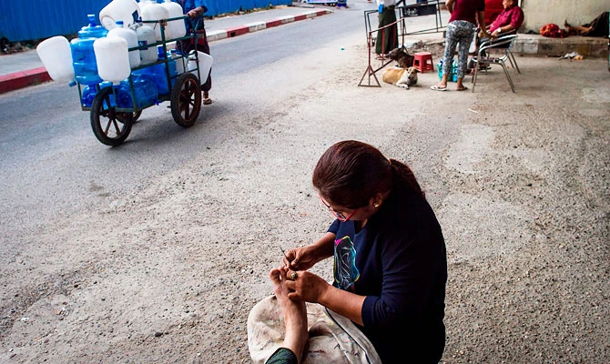 This photo taken on December 4, 2018 shows manicurist Khin Ohn Myint cleaning the nails of a customer under a bridge along Pansodan Street in Yangon. (AFP)