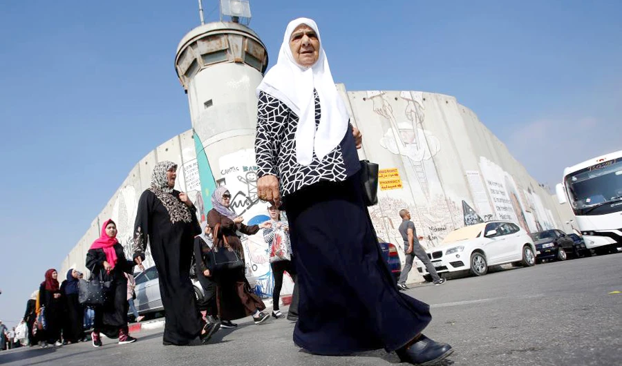 Palestinians pass by a controversial Israeli barrier in Bethlehem in occupied West Bank, on their way to attend Friday prayer at Jerusalem’s Al-Aqsa Mosque. (Reuters)