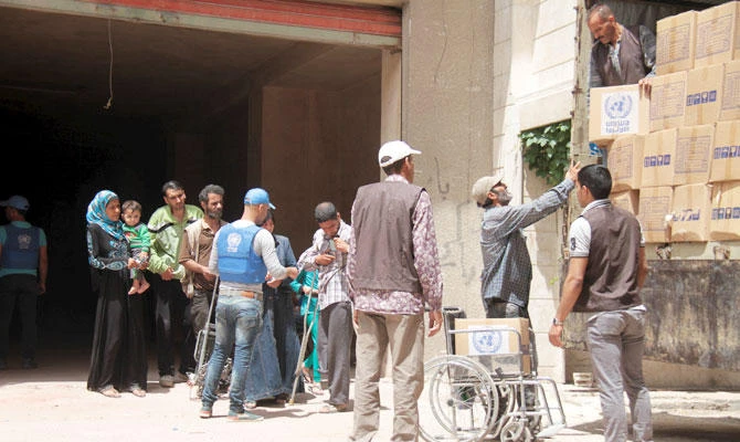Residents and Palestinians who fled the Yarmouk refugee camp receive parcels of humanitarian aid from the United Nations Relief and Works Organization (UNRWA) in the beseiged southern outskirts of Damascus. (REUTERS file photo)