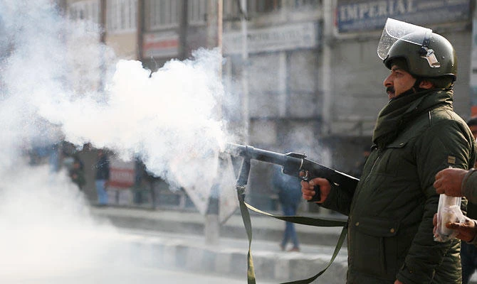 An Indian police officer fires tear smoke shell on Kashmiri protesters attempting to march to an Indian military base in Srinagar, Indian-controlled Kashmir, Monday, Dec. 17, 2018. (AP)