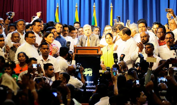 Sri Lanka's reinstated Prime Minister Ranil Wickeremesinghe, center, surrounded by his supporters speaks after assuming duties in Colombo on Sunday. (AP)