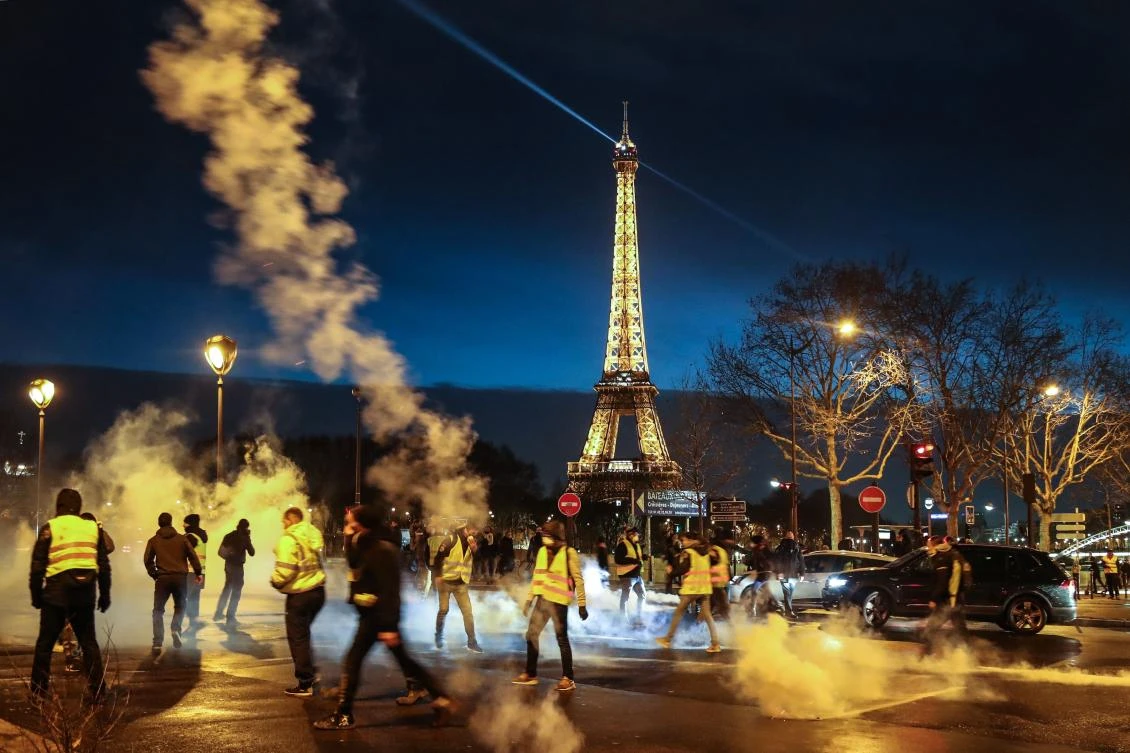 Demonstrators of the French “yellow vests” (gilets jaunes) throws tear gas canisters back as police disperse the end of a protest in central Paris on December 22, 2018 as the movement turned out in small numbers for a sixth Saturday of nationwide demonstrations. (AFP)