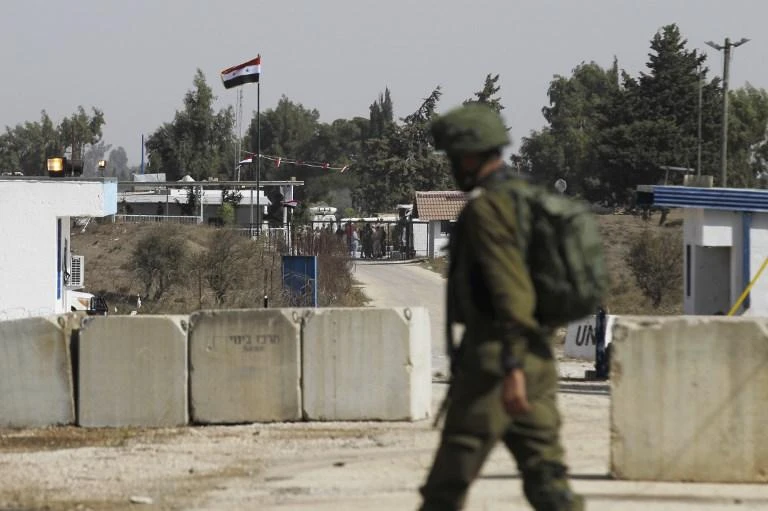 An Israeli soldier walks opposite Syria's national flag (C) on the Israeli side of the Quneitra crossing which opened on October 15, 2018 into the Syrian side of the Golan Heights. (File/AFP)