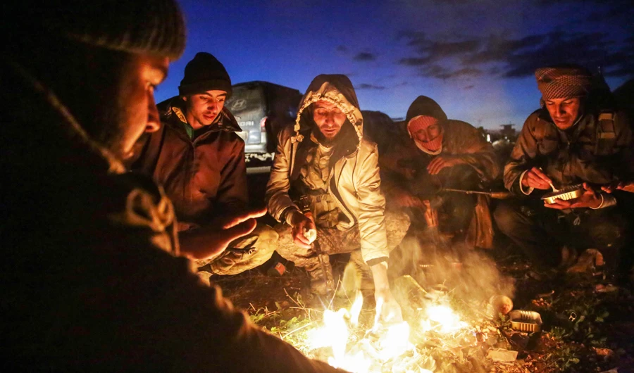 Turkish-backed Syrian fighters warm up around a fire at a position near the northern Syrian town of Manbij. (AFP)