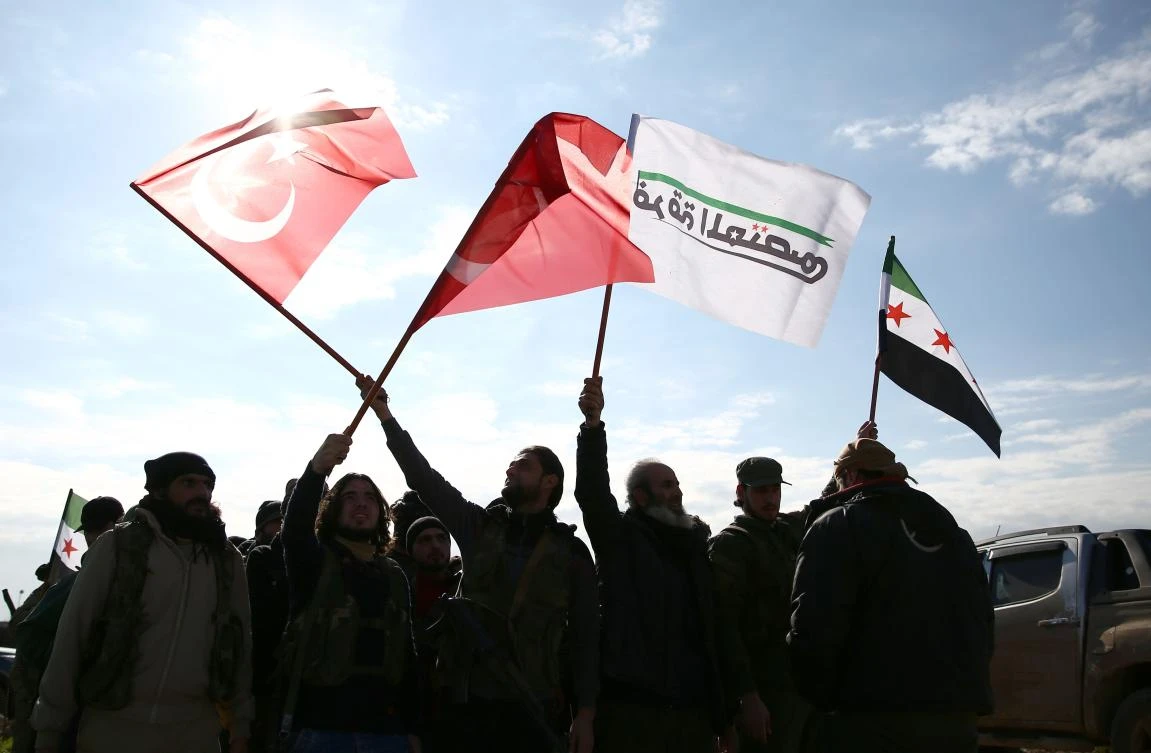 Turkish-backed Syrian fighters wave Turkish and opposition flags as they gather in the north of Aleppo province before heading to the Kurdish-controlled town of Manbij, on December 29, 2018. (AFP)