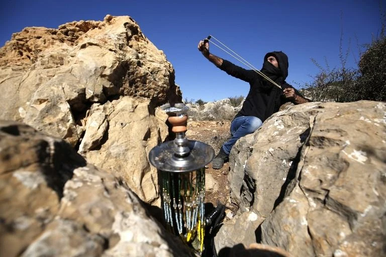 A Palestinian hurls stones at Israeli troops during a protest against Israeli land seizures for Jewish settlements, in Al-Mazraah Al-Gharbiyah village near Ramallah on November 2. (AFP)