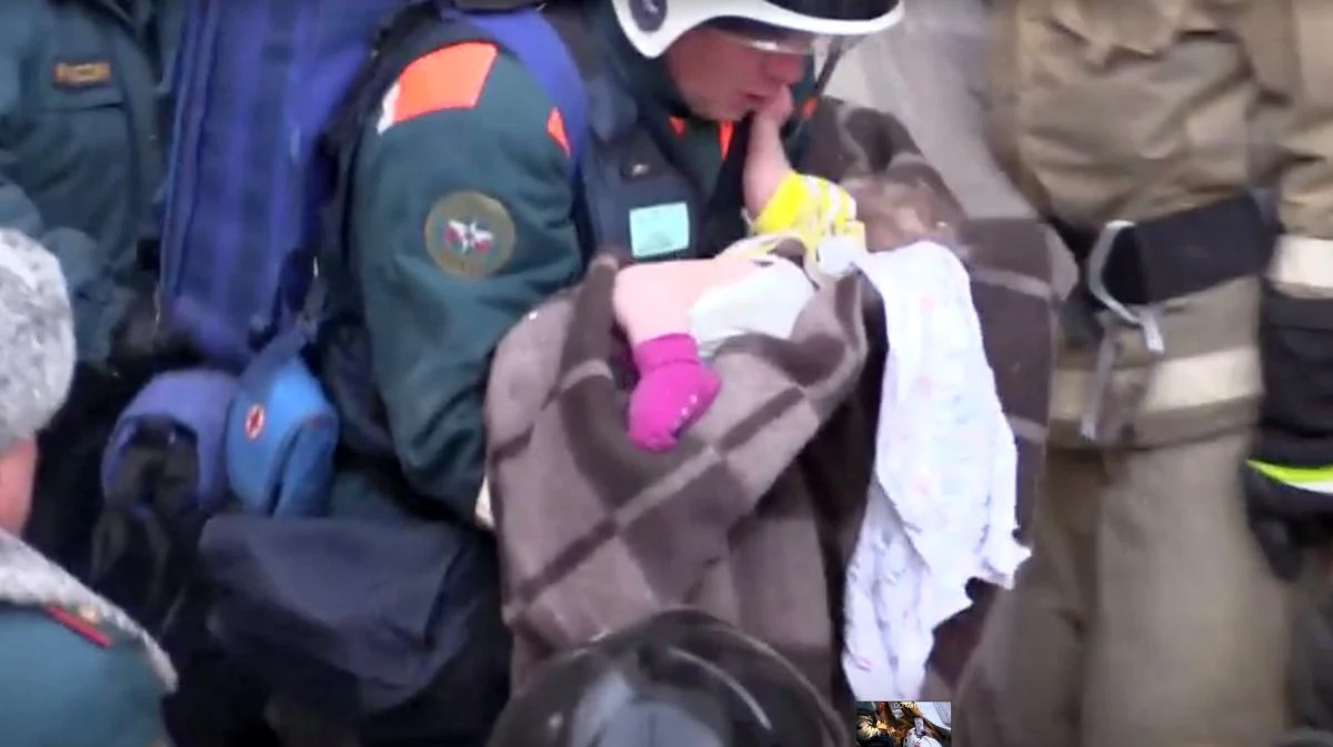 A still image taken from a video footage shows a rescuer carries a 11-month-old child found alive in the rubble of a Russian apartment block that partially collapsed after a suspected gas blast in Magnitogorsk, Russia January 1, 2019. (Reuters)