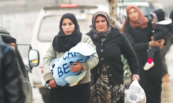 Syrian women carry children in the northern town of Manbij on Turkish border, which is controlled since 2016 by an alliance of Kurdish and Arab fighters backed by the US-led coalition. (AFP)