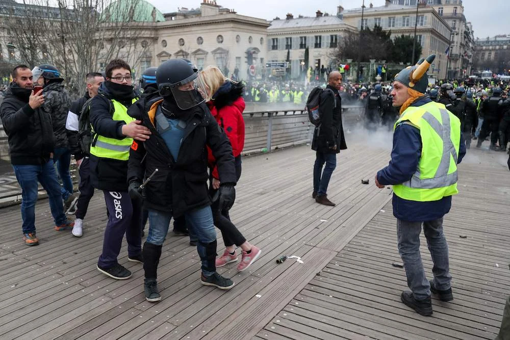 A security official (C) is restrained as he speaks with a yellow vest "Gilets Jaunes" anti-government protestor (R) during a rally in Paris on January 5, 2019. (AFP)