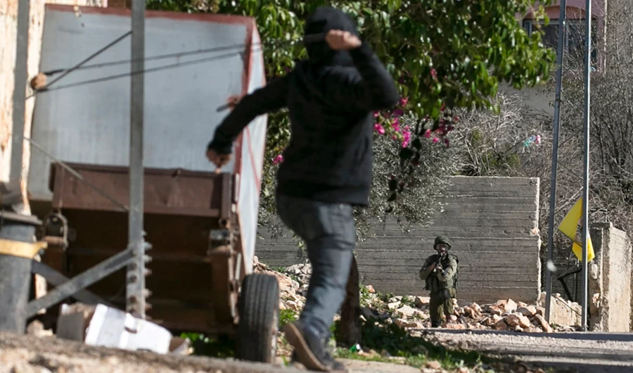 A Palestinian protester throws stones at an Israeli soldier in the village of Kfar Qaddum, near Nablus in the occupied West Bank. (AFP)