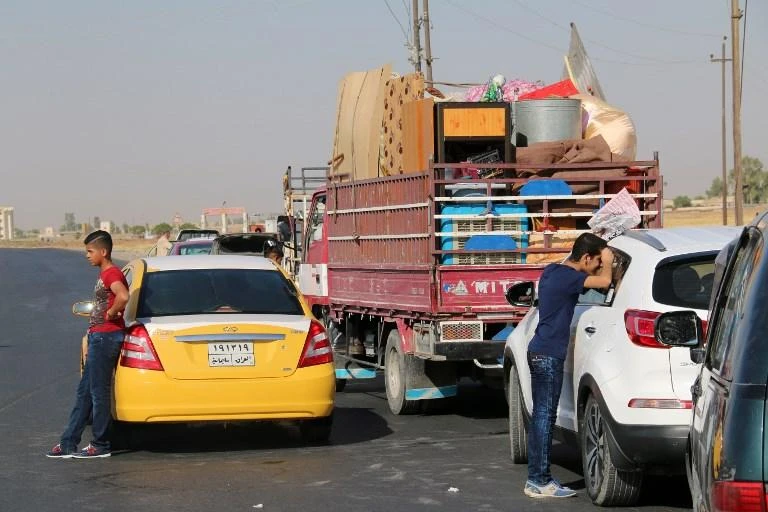 Displaced Iraqis wait next to their vehicles as they get ready to return home to Tikrit in this July 22, 2015 photo after government forces retook the city from Daesh a few months earlier. (AFP)