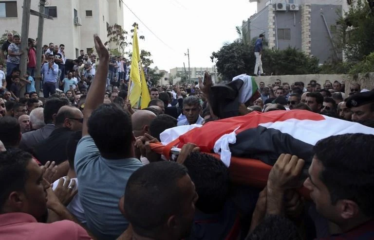 Palestinians carry the body of 48-year-old mother of eight, Aisha Rabi, who died of her wounds after the car she was travelling in with her husband was hit by stones, during her funeral in the West Bank village of Bidya, near Salfit. (AFP)