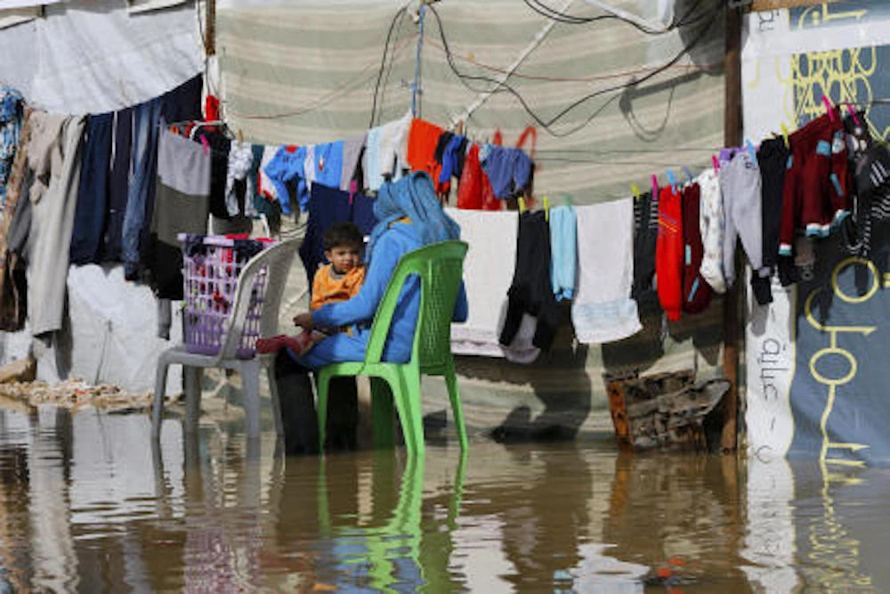 A Syrian refugee hangs clothes to dry at a flooded refugee camp in the town of Bar Elias, in the Bekaa Valley, Lebanon. (AP)